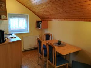 cocina y comedor con mesa de madera y sillas en Apartman Mercédesz II., en Zalakaros