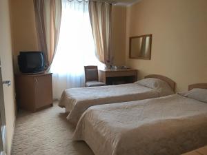 a hotel room with two beds and a television at Готель Ягодин in Starovoitove