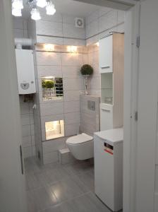 a white bathroom with a toilet and a sink at APARTAMENT CENTRUM Węgorzewa in Węgorzewo