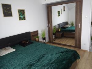 Un dormitorio con una gran cama verde y un espejo en APARTAMENT CENTRUM Węgorzewa, en Węgorzewo