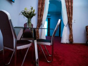 un tavolo di vetro con sedie e un vaso di fiori di Relaxe Palace Hotel a Yaoundé
