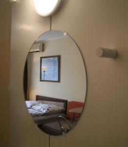 a mirror reflecting a bedroom with a bed and a chair at Víctor Hugo Central Apartment in Budapest