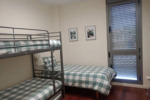 two bunk beds in a room with a window at Apartamento en Urb. Las Margas Golf (piscina) in Sabiñánigo