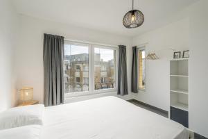 a bedroom with a white bed and a large window at Panne a Côte in De Panne