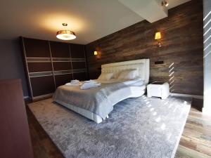 - une chambre avec un grand lit et un mur en bois dans l'établissement Edžio apartamentai, à Palanga