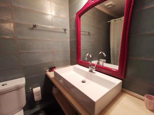 uma casa de banho com um lavatório branco e um espelho vermelho em Puppet Guesthouse em Corfu Town