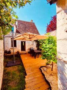 une terrasse en bois avec une table et un parasol dans l'établissement Le Lavoir aux Roses by Gîtes Sud Touraine, à Chédigny
