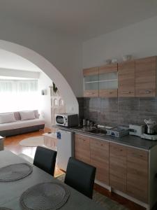 a kitchen with wooden cabinets and a living room at Viola Apartmanház in Bogács