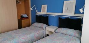 two beds in a room with blue walls at Apartamento Malpica de Bergantiños in Malpica