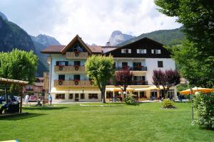 a large building with a lawn in front of it at Garden Hotel Bellariva in Molveno