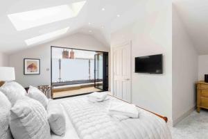 a white bedroom with a bed and a tv at Exceptional, boutique retreat Bath road Cheltenham in Cheltenham