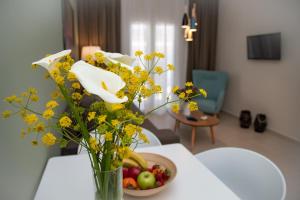 eine Vase mit gelben Blumen und eine Schale Obst auf dem Tisch in der Unterkunft Kassiopi Luxury Suites in Kassiopi