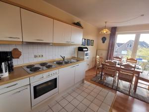 a kitchen with white cabinets and a dining room with a table at Strandbad in Horumersiel