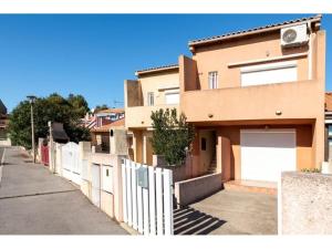 a house with a white fence next to a street at Studio mezzanine St pierre la mer in Saint Pierre La Mer