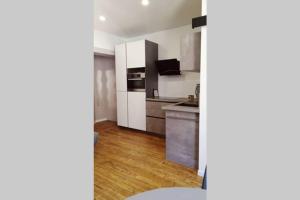 cocina con armarios blancos y suelo de madera en L'oasis : Appartement en centre ville, en Abbeville