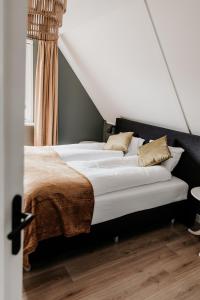 a bed with white sheets and pillows in a room at Vakantiehuis 6 personen in de Achterhoek met sauna in Lievelde