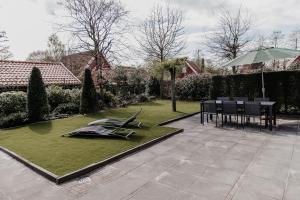 a garden with a table and chairs and an umbrella at Vakantiehuis 6 personen in de Achterhoek met sauna in Lievelde