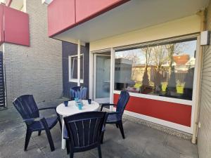 d'une terrasse avec une table et des chaises devant une fenêtre. dans l'établissement Nordseegras, à Horumersiel