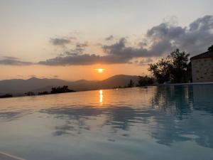 a swimming pool with the sunset in the background at Astrali Stone Villas in Paramythia