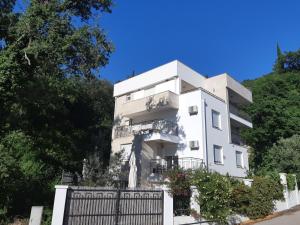 Ein weißes Gebäude mit einem Zaun davor. in der Unterkunft Apartments Villa Simonovic in Petrovac na Moru
