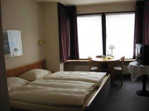 a bedroom with a bed and a table and window at Hotel Pfälzer Hof, Zum Schokoladengießer in Rodalben