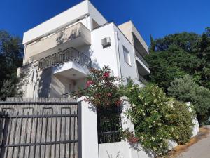 a white house with a fence and flowers at Apartments Villa Simonovic in Petrovac na Moru