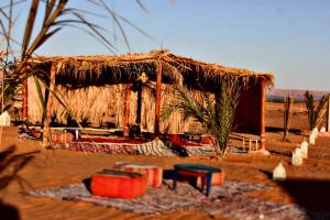 a straw hut with a rug in front of it at Krich Camp in Merzouga