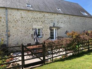 a brick building with a wooden fence and a bench at The Old Farm Gite in Amfreville