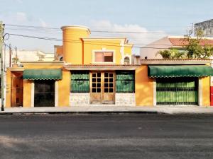 um edifício amarelo com portas verdes numa rua em Hotel Casa Mallorca em Cancún