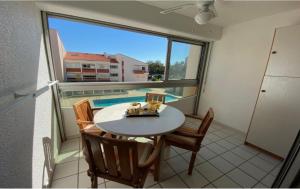 a dining room with a table and chairs and a large window at ARGELES PLAGE STUDIO PISCINE PARK. PRIVATIF DANS RES. SECURISEE in Argelès-sur-Mer