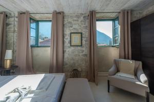 a bedroom with a bed and a chair and windows at Apartments Gabela in Risan +43 photos