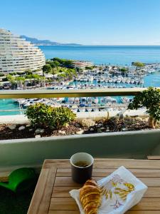 a cup of coffee and a croissant on a table with a view at Marina Baie des Anges in Villeneuve-Loubet