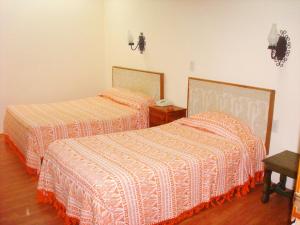 a bedroom with two beds with orange and white sheets at Hotel Don Quijote in San Cristóbal de Las Casas