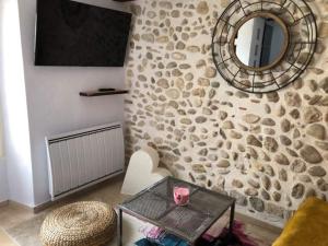 - un salon avec un mur en pierre et un miroir dans l'établissement Entre lac et lavandes, à Roumoules