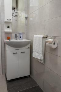 a white bathroom with a sink and a mirror at Vikendica Julka Palić in Palić