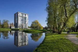 a building is reflected in the water of a river at ParkView Apartment in Gdańsk