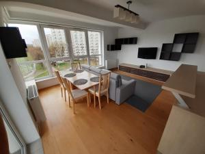 ein Wohnzimmer mit einem Tisch und Stühlen sowie eine Küche in der Unterkunft ParkView Apartment in Danzig