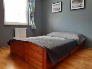 a bed with a wooden frame in a room with a window at ParkView Apartment in Gdańsk