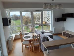 ein Wohnzimmer mit einem Tisch und Stühlen sowie einem großen Fenster in der Unterkunft ParkView Apartment in Danzig