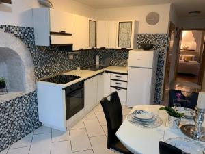 eine Küche mit weißen Schränken und einem Tisch mit einem Esszimmer in der Unterkunft First row to the sea - Maremi Izola Apartment terrace in Izola