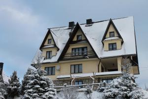 una casa con techo de gambrel en la nieve en Pokoje Janka Gliczarów Górny, en Gliczarów Górny