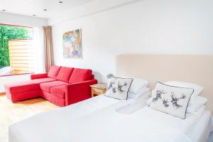 Habitación con cama y sofá rojo en Lavik Fjord Hotel & Apartments en Lavik