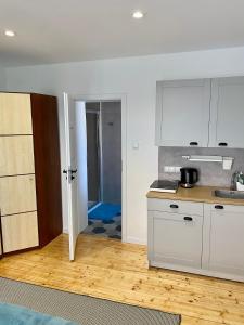 a kitchen with white cabinets and a wooden floor at Apartament na Nadmorskiej in Grzybowo