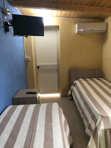Zimmer mit 2 Betten und einer Tür mit einem TV in der Unterkunft Casa Relax Avola in Avola