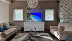 uma sala de estar com 2 sofás e uma televisão de ecrã plano em Villa Bubica- cozy holiday home in rural area with pool em Stankovci