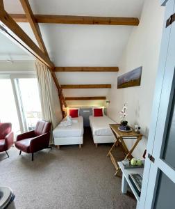 Cette chambre comprend deux lits, une table et des chaises. dans l'établissement Havenhotel At Sea Texel, à Oudeschild