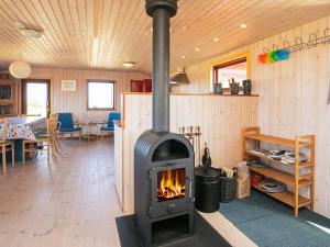 a wood burning stove in a room with a table at Three-Bedroom Holiday home in Løkken 31 in Grønhøj