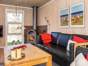 a living room with a leather couch and a fireplace at 6 person holiday home in Hemmet in Falen