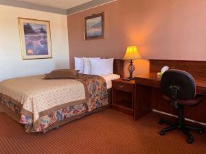 a hotel room with a bed and a desk and a chair at Value Lodge Inn in Delta