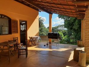 a patio with a grill and a table and chairs at Sitio Carvalho da Serra in Caeté